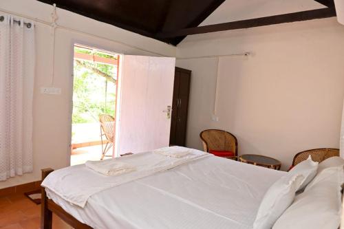 a bedroom with a white bed and a large window at Philosopher's Stone in Varkala