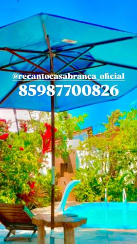 a blue umbrella sitting on a table with a bench at Casa em Mundaú Trairi-Ce in Trairi