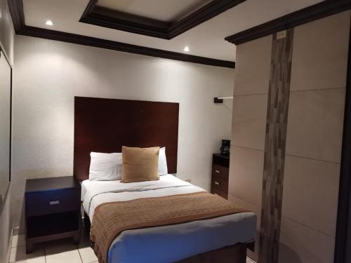 a bedroom with a bed with a wooden headboard at Hotel Don Quijote in Mexicali
