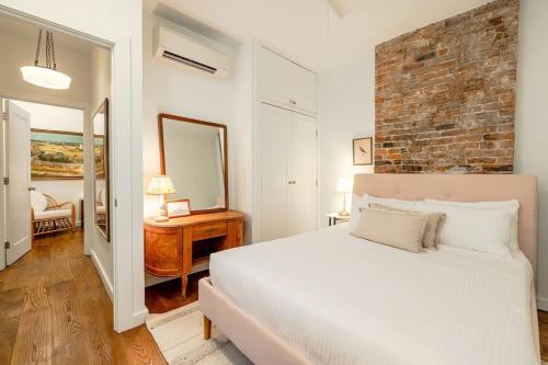 Un dormitorio con una cama blanca y una pared de ladrillo. en Walk to ALL - Washington Park - Gorgeous 2BR Condo, en Cincinnati