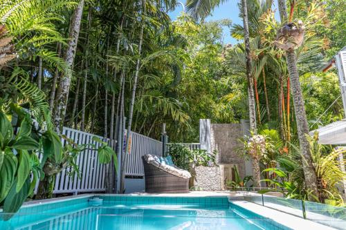 a swimming pool with palm trees in a backyard at Courtyard on Murphy Tropical Oasis in Town in Port Douglas