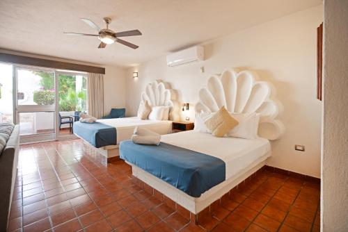 a bedroom with two beds and a living room at Hotel & Suites El Moro in La Paz