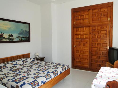 a bedroom with a bed and a tv and a door at Los Geraneos in Águilas