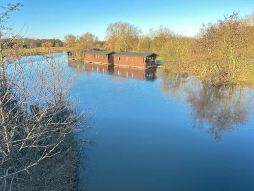 a river with two boats on the water at Wroxham Broads Lodge Houseboat in Bellaghy