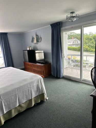 a bedroom with a bed and a window with a balcony at Sands Of Time Motor Inn & Harbor House in Woods Hole
