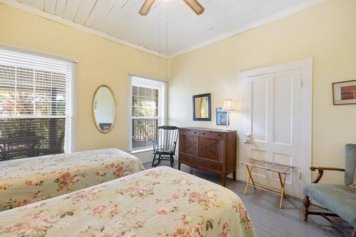 a bedroom with two beds and a dresser and a chair at Cedar Keys Island Hotel in downtown in Cedar Key
