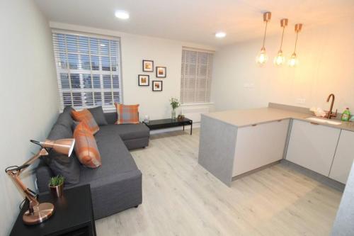 a living room with a gray couch and a kitchen at Charming Modern 2br Flat In Central Preston in Preston