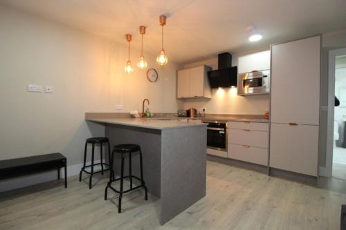 a kitchen with a counter and two bar stools at Charming Modern 2br Flat In Central Preston in Preston