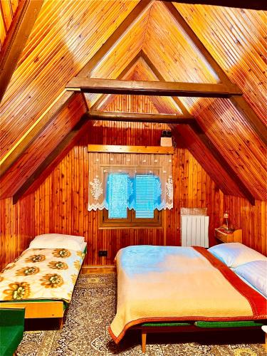 two beds in a room with wooden walls at Chata ALPINA 1 in Tatranská Lomnica