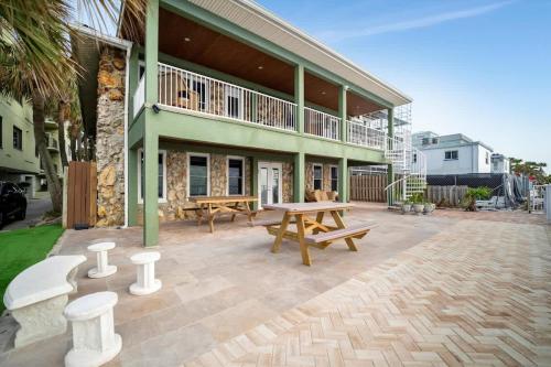 eine Terrasse mit Picknicktischen und ein Gebäude in der Unterkunft Stones Throw Beachside Bungalow #1 ON THE BEACH in Clearwater Beach