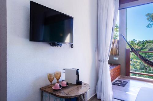 a room with a tv and a table with wine glasses at Hotel Vila Kebaya in Ilhabela