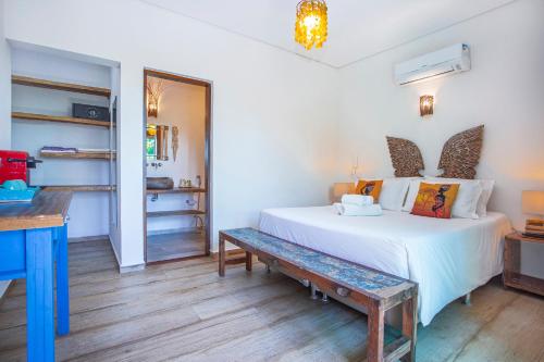 a bedroom with a white bed and a bench at Hotel Vila Kebaya in Ilhabela