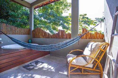 a hammock on a porch with a chair and a tub at Hotel Vila Kebaya in Ilhabela