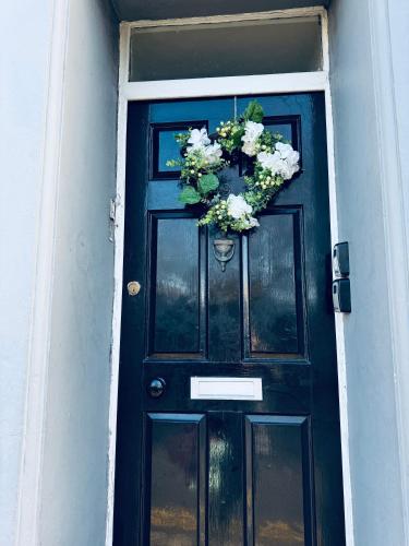 a black door with a wreath of flowers on it at The Georgian Townhouse - 4 Bedrooms - Sleeps 9 in Whitehaven