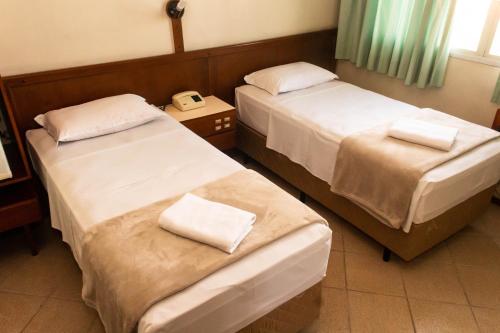 a hotel room with two beds and a telephone at HOTEL DOMHOF in Blumenau