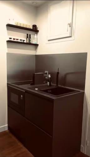 une cuisine noire avec un évier et une fenêtre dans l'établissement Chic Studio - Montorgueil, AC & Fast Wi-fi, à Paris