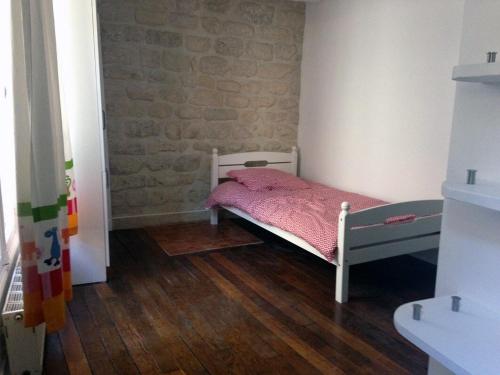 Cette petite chambre comprend un lit avec des draps roses. dans l'établissement Charming 2-bedroom duplex Bastille, à Paris