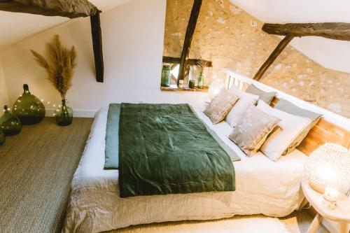 a bedroom with a bed with a green blanket on it at Gite romantique avec Sauna, Spa, Home cinéma -La Closerie du Biard- in Beaumont-du-Périgord
