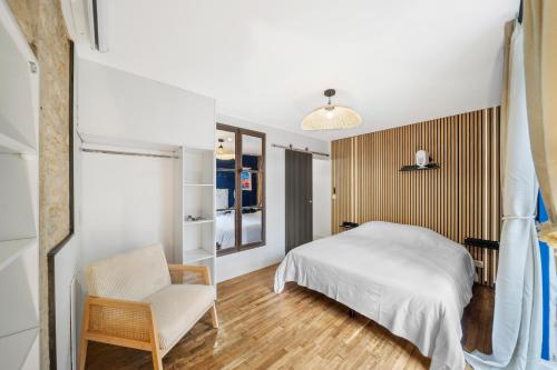 une chambre avec un lit et une chaise dans l'établissement Oenosuite - Charme & Vin en hyper-centre, à Dijon