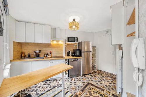 une cuisine avec des armoires blanches et des appareils en acier inoxydable dans l'établissement Oenosuite - Charme & Vin en hyper-centre, à Dijon