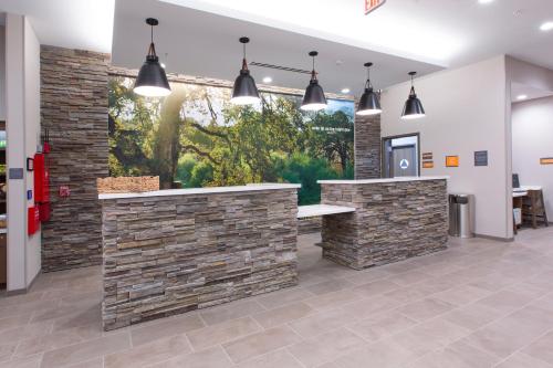 a lobby with a stone wall and pendant lights at La Quinta Inn and Suites by Wyndham Lincoln in Lincoln