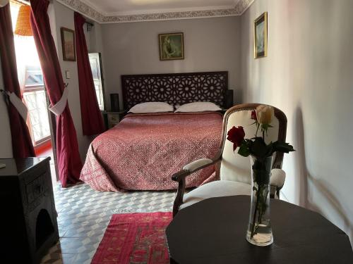 a bedroom with a bed and a vase of roses on a table at Riad Syba in Marrakech