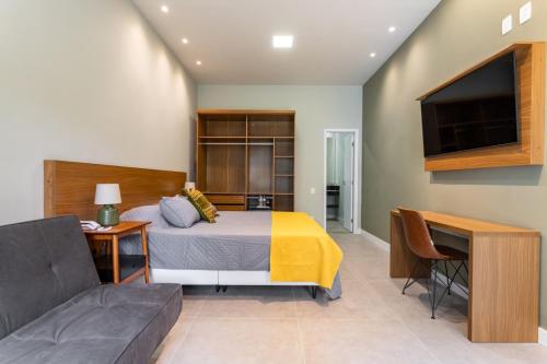 a bedroom with a bed and a couch and a tv at Villa Christa in Rio de Janeiro