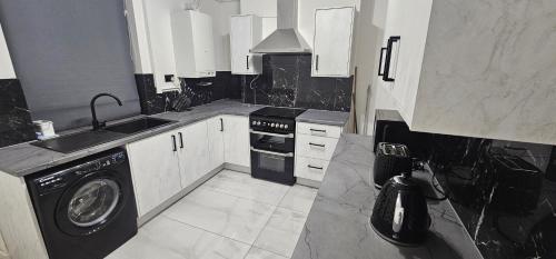 a black and white kitchen with a washing machine at Newly renovated cosy home BB10 in Burnley