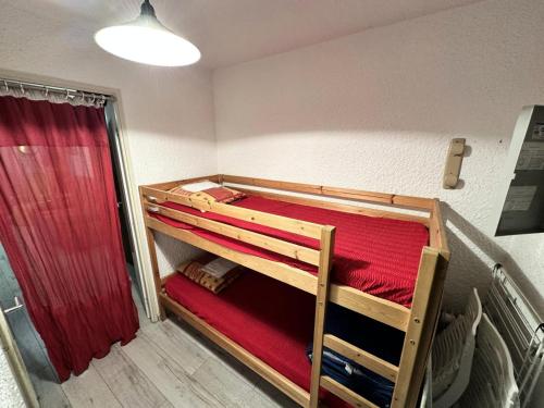 a room with two bunk beds and a red curtain at Résidence Les Quatres Saisons - Appartement à l'entrée du Village de Corrençon, départ des navettes gratuites au pied de la résidence MAE-4004 in Corrençon-en-Vercors