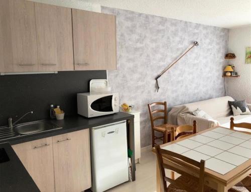 małą kuchnię ze stołem i kuchenką mikrofalową w obiekcie Résidence Les Quatres Saisons - STUDIO VILLAGE CORRENCON MAE-4124 w mieście Corrençon-en-Vercors