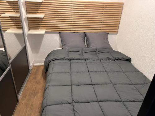 - un lit dans une petite chambre avec une tête de lit en bois dans l'établissement Appartement vue sur les Pyrénées 4pers aux pieds des pistes, à Ax-les-Thermes