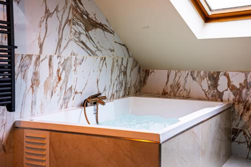 a bathroom with a bath tub with a sink at La Marble Room - Suite balnéo & sauna in Angers