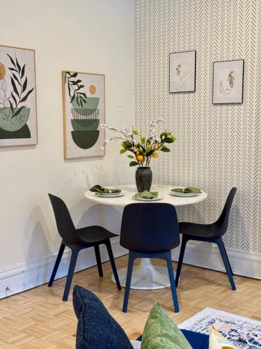 a dining room table with chairs and a vase of flowers at Chic Living on Newbury Street in Boston