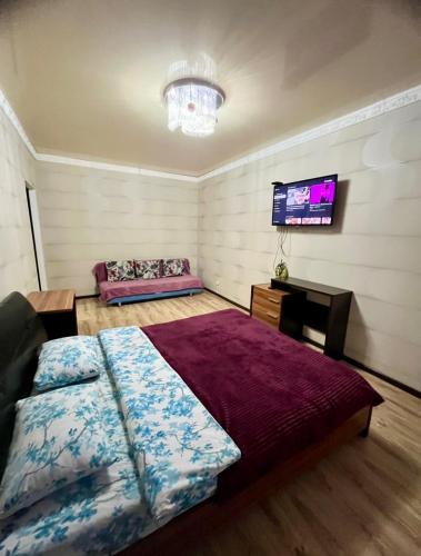 a bedroom with a bed and a flat screen tv at Двухкомнатная квартира в ЖК Жана Алем in Atyraū