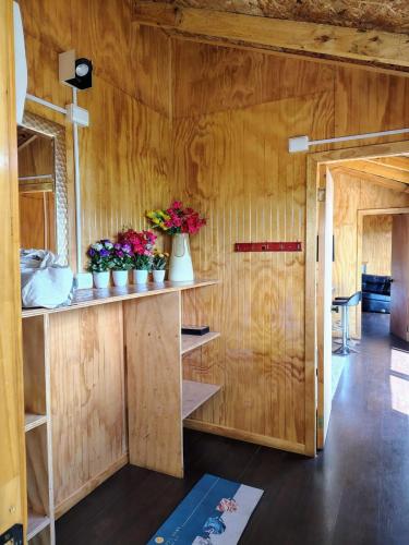 a room with wooden walls and flowers on shelves at Cabañas vista Yates in Puerto del Yate