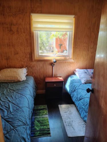 two beds in a small room with a window at Cabañas vista Yates in Puerto del Yate