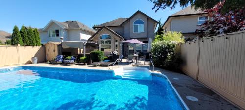 a swimming pool in front of a house at Metropolitan Dream Stay with Saltwater Pool and Hot Tub in Surrey