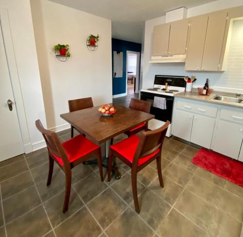 ベー・サン・ポールにあるEspace cozy au coeur de Baie-St-Paulのキッチン(木製テーブル、赤い椅子付)