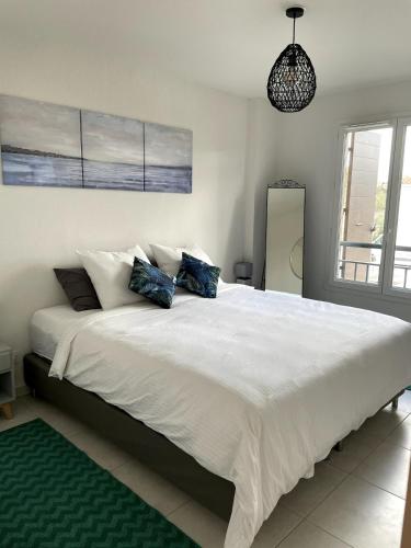 une chambre avec un grand lit blanc avec des oreillers bleus dans l'établissement Maison Jasmin, Modern, air-conditioned 2-bed with lovely terrace & communal pool, au Plan-de-la-Tour