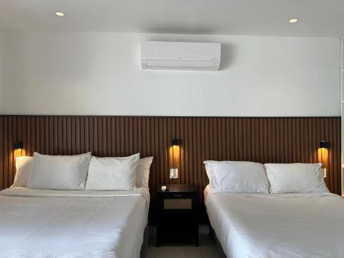 two beds in a hotel room with white sheets at Villa Condesa Del Mar in Contadora