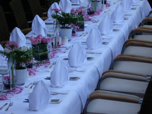 a row of tables with white plates and flowers on them at Hotel Alpenhof Postillion in Kochel