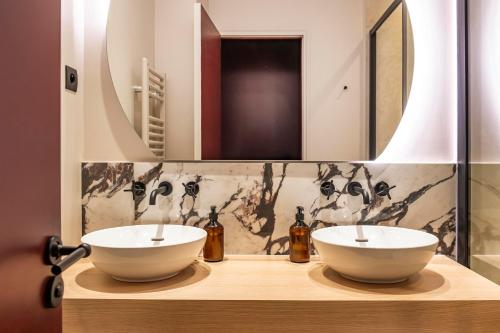 une salle de bain avec deux lavabos et un miroir dans l'établissement The Olympia Suite - Duke Housing, à Paris