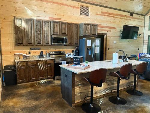 cocina con armarios de madera y barra con taburetes en The Cozy Endless Sunset Cabin!, en Broken Bow