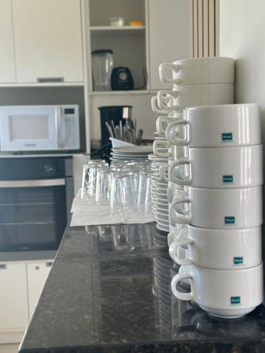 a kitchen counter with a stack of cups and plates at Hotel Palmeiras in Santana do Livramento