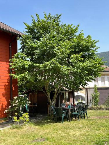 a table and chairs under a tree in a yard at Villa Olian - au cœur du Val-de-Travers in Travers
