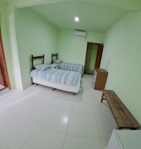 a bedroom with two beds and a dresser in it at Pousada Recanto do Japa in Nilo Peçanha