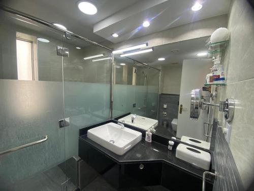 Dinar - cozy master bedroom في أبوظبي: حمام مزود بحوض ومِرآة