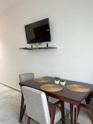 a dining room table with chairs and a television on a wall at Departamento en zona centro de chapala #3 in Chapala