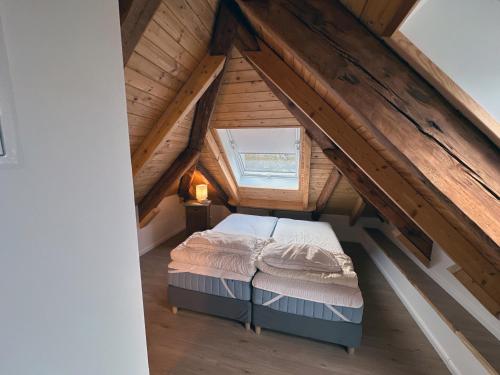 an attic bedroom with a bed and a window at Lassen Hof Ferienwohnung 01 Bienenstock in Brodersby