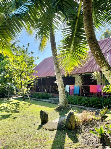 a house with two palm trees in front of it at Punatea Village in Afaahiti